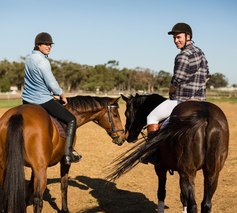 two-male-friends-riding-horse-in-the-ranch.jpg